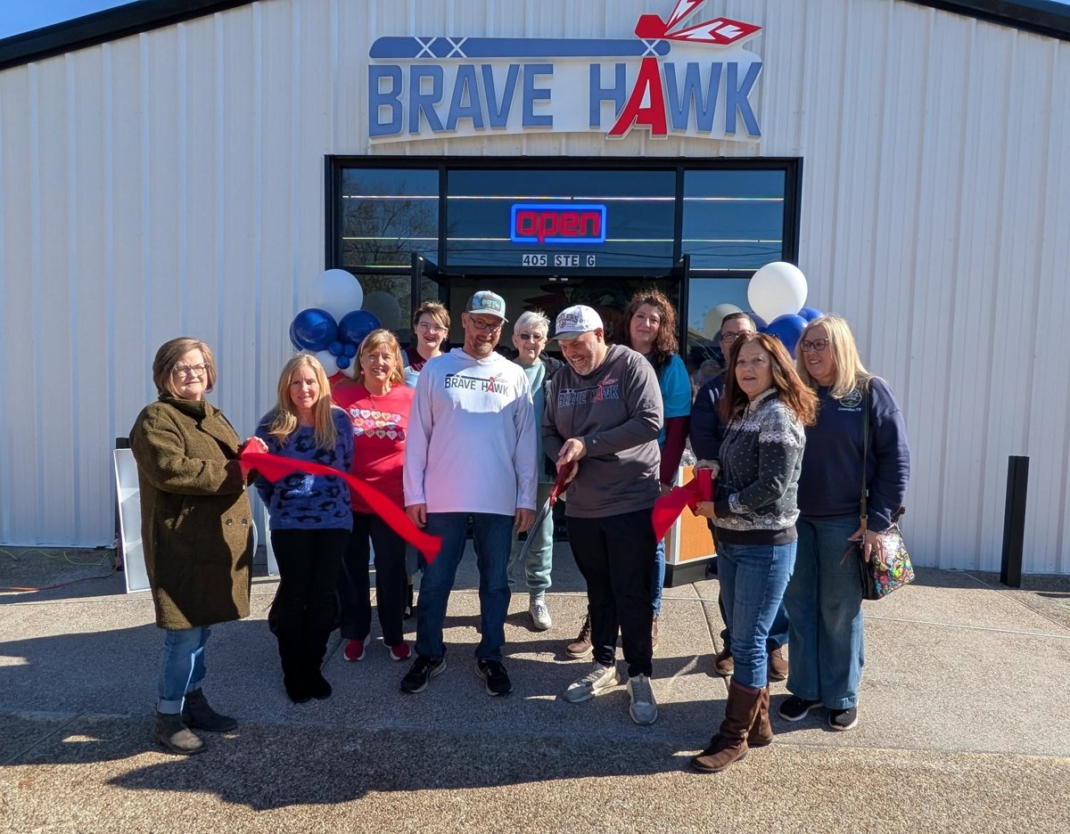 Chamber members and the owners of Brave Hawk Sports hold a ribbon in front of the business’s new building
