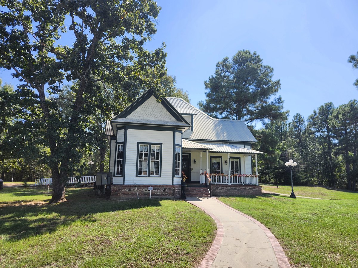 The white two-story Chandler Museum house with a wide front porch and brick-edged walkway