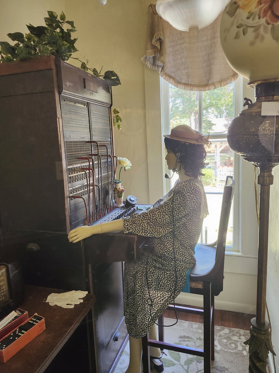 A mannequin operator seated at a replica telephone switchboard
