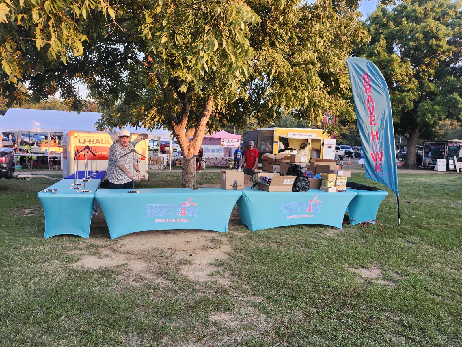 The Brave Hawk Sports booth being set up under the trees at Winchester Park