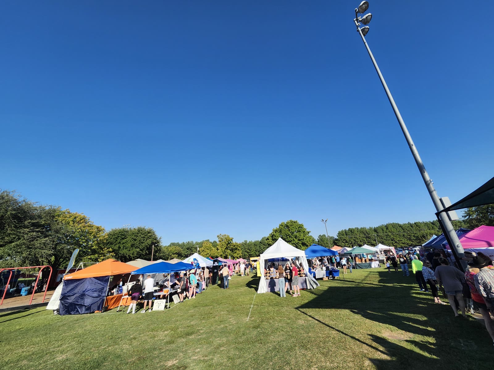 Shoppers walk past rows of vendor tents at Winchester Park