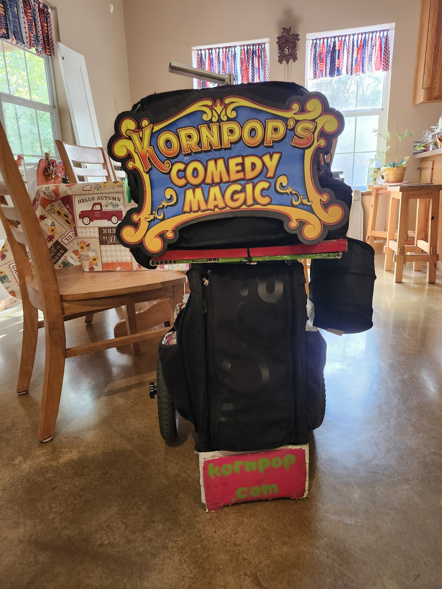Kornpop’s “Comedy Magic” show case on wheels, with a kornpop.com sign