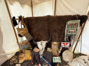 A tent display of a buffalo hide, skull, beaded bags and Native American relics