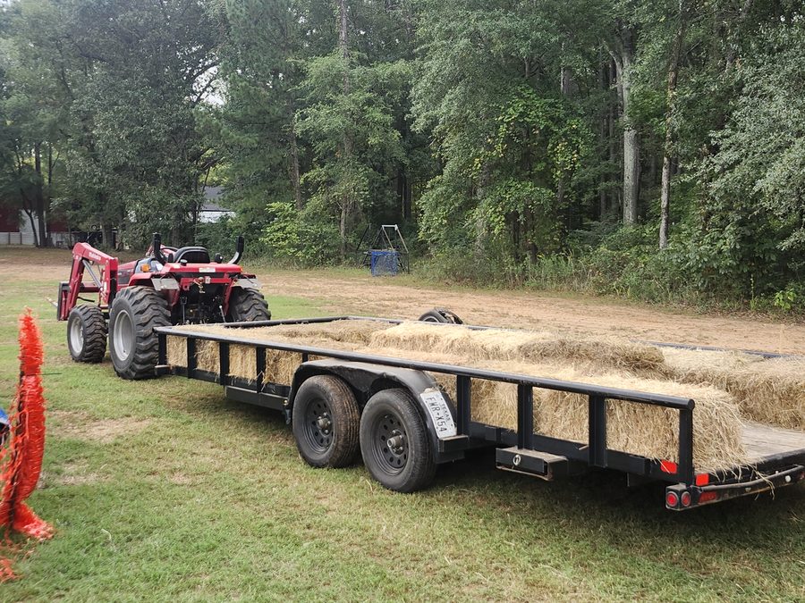 A red tractor hitched to a hay-lined trailer waits to carry guests around the grounds