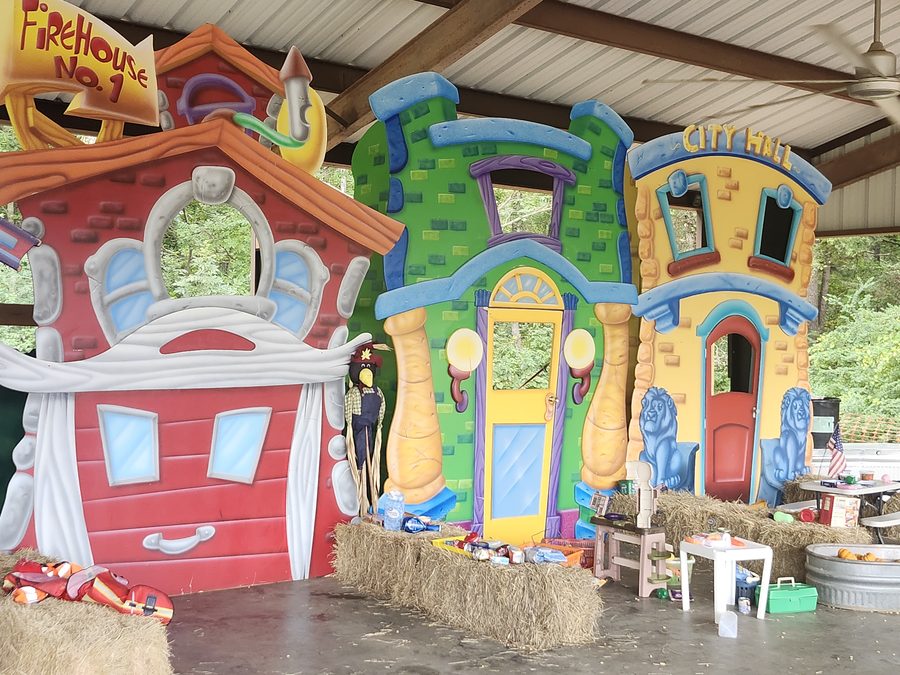 Brightly painted playhouses, including a firehouse and city hall, line Pumpkin Place Village under the pavilion