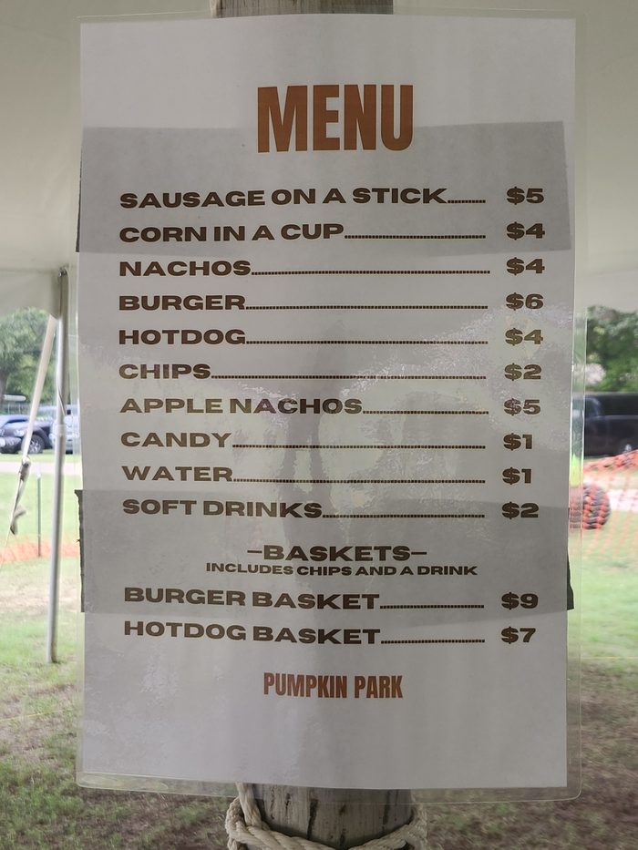 The Pumpkin Park concessions menu offers sausage on a stick, corn in a cup, burgers, hot dogs and more, with baskets that include chips and a drink